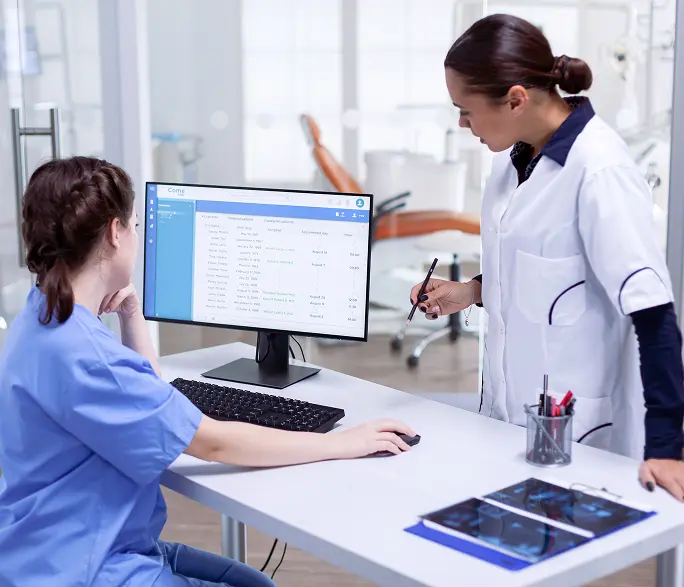 Clinicians reviewing a claims platform at a clinic workstation